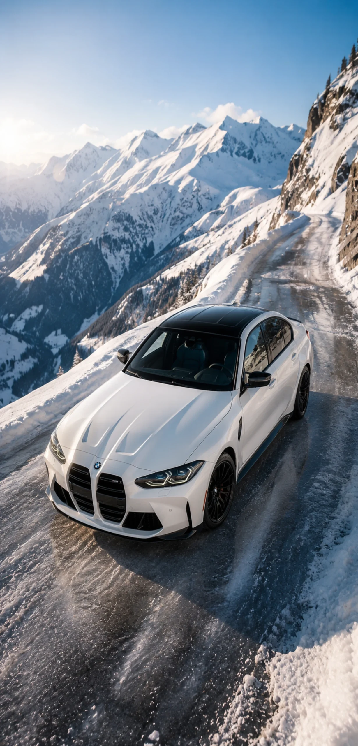 Weißer BMW auf einer verschneiten Alpenstraße mit schneebedeckten Bergen und blauem Winterhimmel.