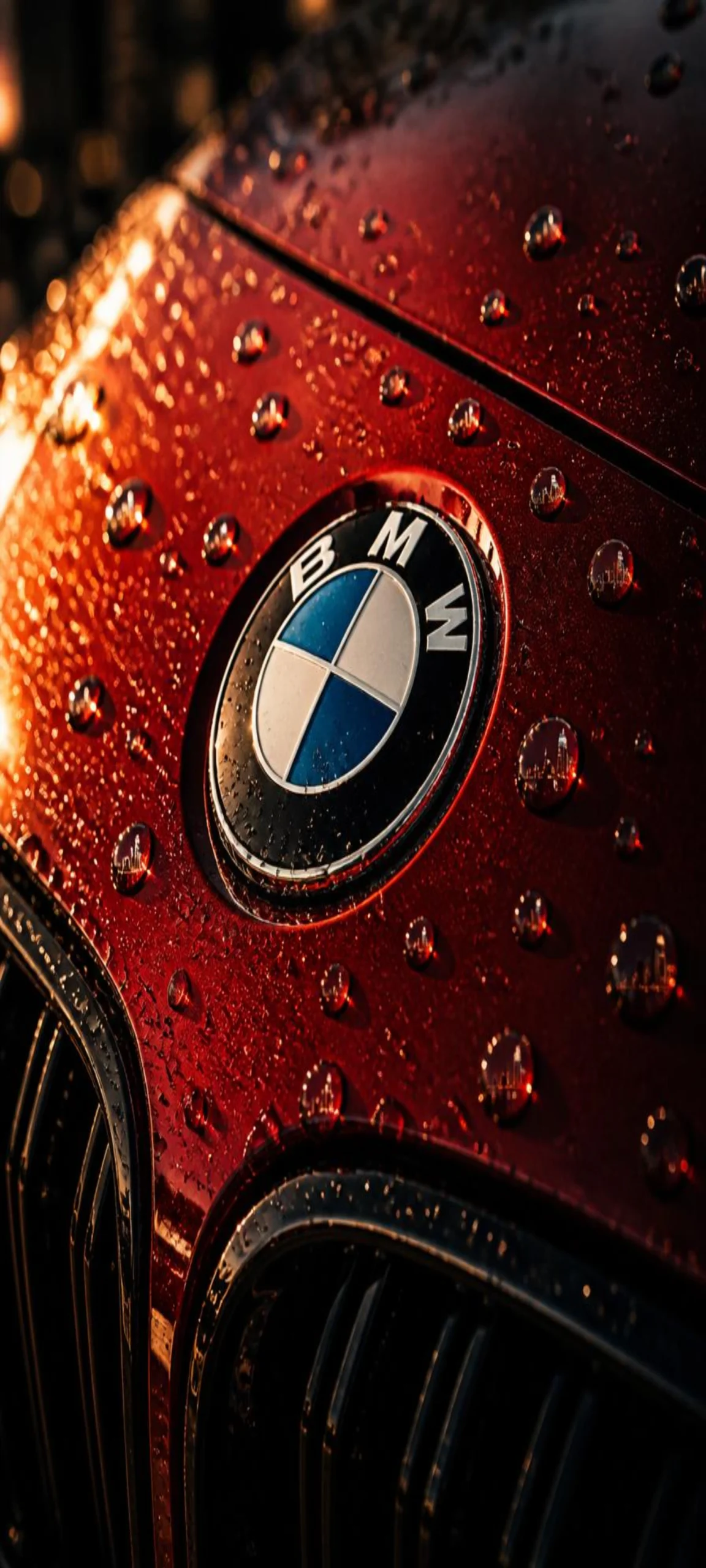 Makroaufnahme des BMW Logos auf rotem Lack mit glänzenden Regentropfen als hochwertiges 4K Smartphone Wallpaper.