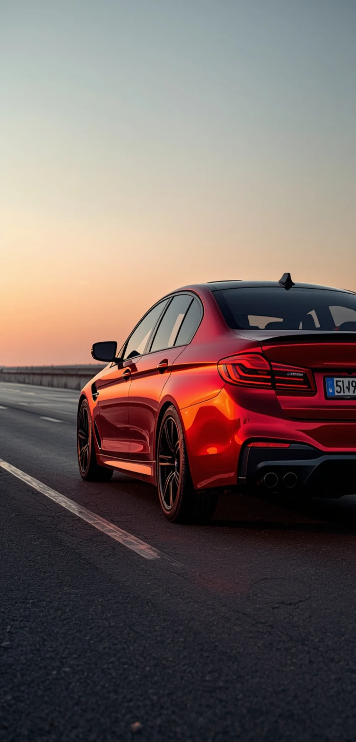 Roter BMW M5 aus der Heckansicht auf einer leeren Straße bei Sonnenuntergang mit warmem Himmel und glänzendem Metallic-Lack – hochwertiges Smartphone-Hintergrundbild.